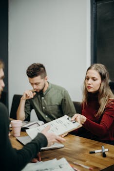 pexels photo 3205567 3205567 A team of adults discussing documents in an office meeting setting, focusing on collaboration.